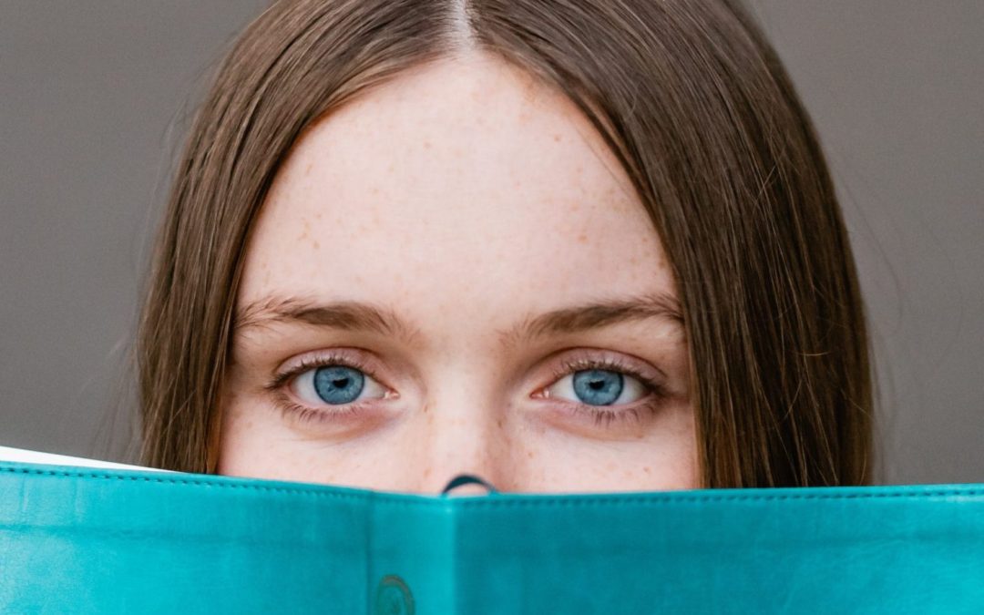woman covering her face with teal book